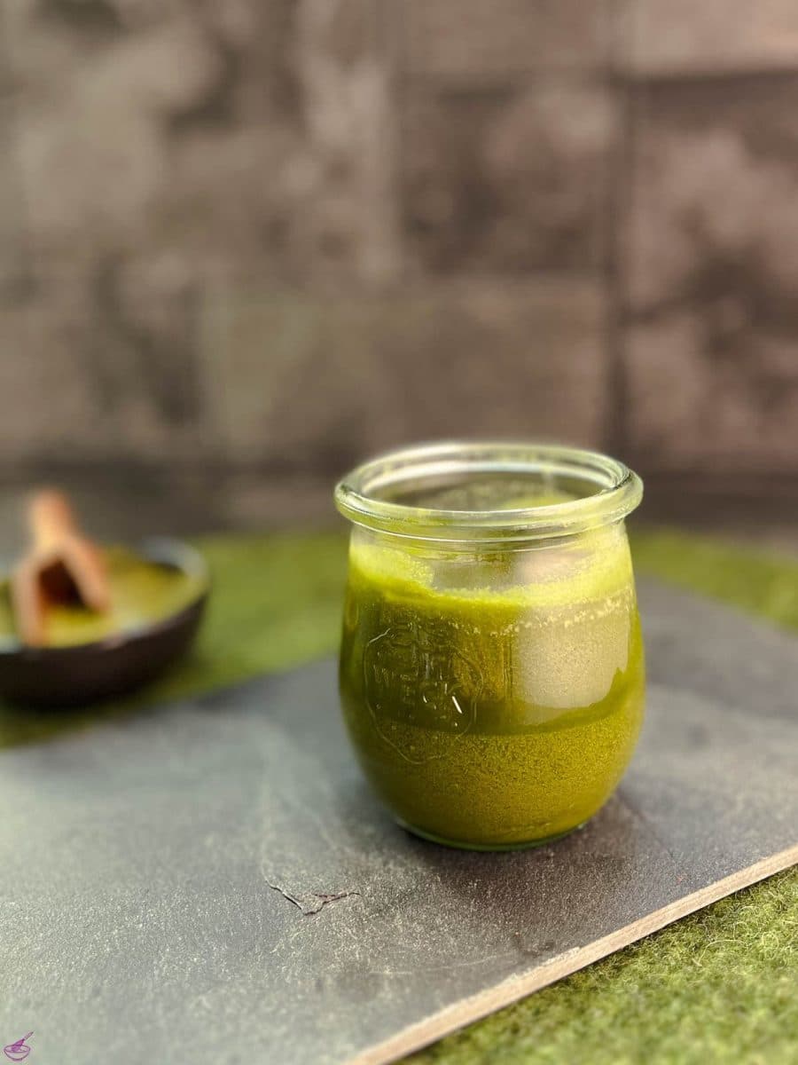 A preserving jar filled with Matcha butter (after cooling) on a slate plate.