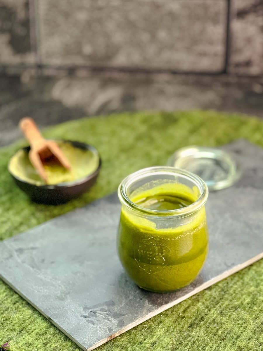 A preserving jar filled with Matcha butter (after cooling) on a slate plate.