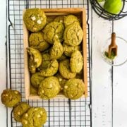 Delicious white chocolate chip matcha cookies with a hint of lime flavor - chewy and soft at the same time. Placed on a wooden tray and cooling rack.