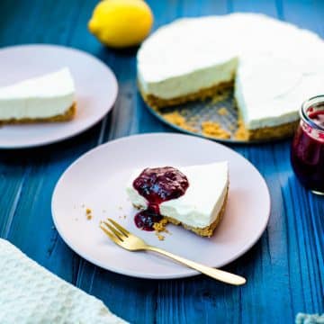 Refreshing lemon cheesecake slice with blueberry sauce on dark blue wooden background.