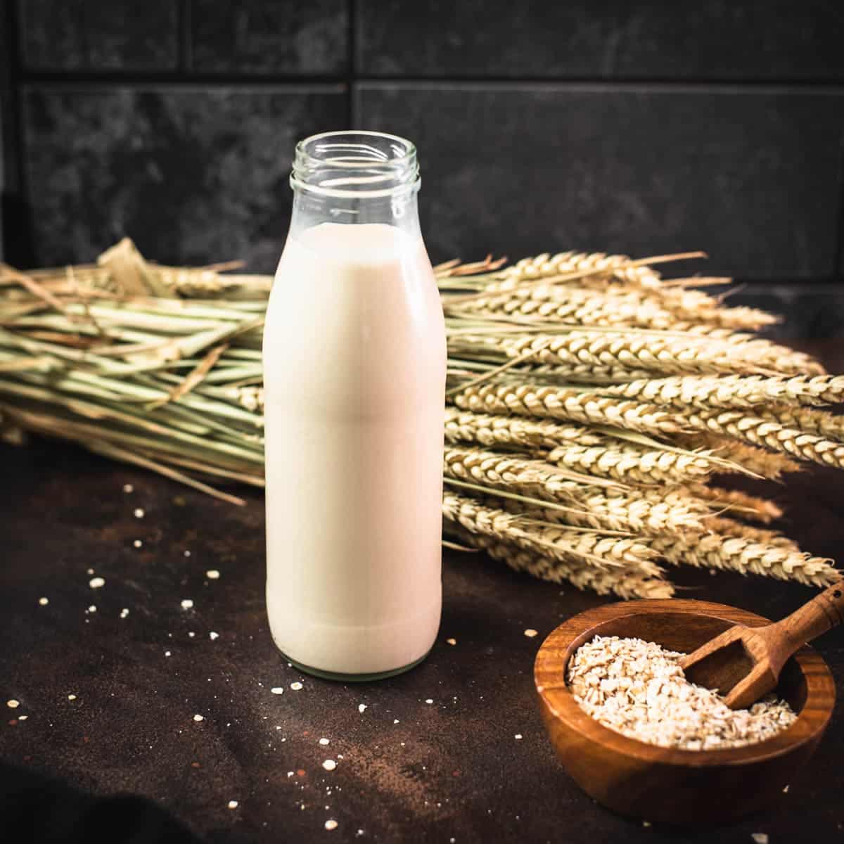 Milk bottle with oat milk on dark background.