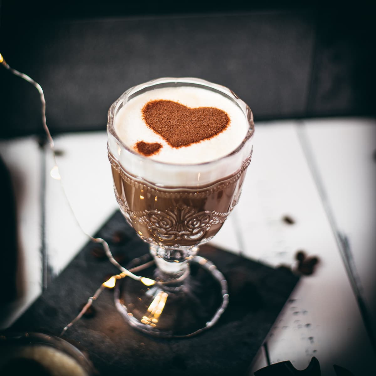 Divine coffee con leche in gorgeous glass, garnish with 2 dusted cocoa hearts.