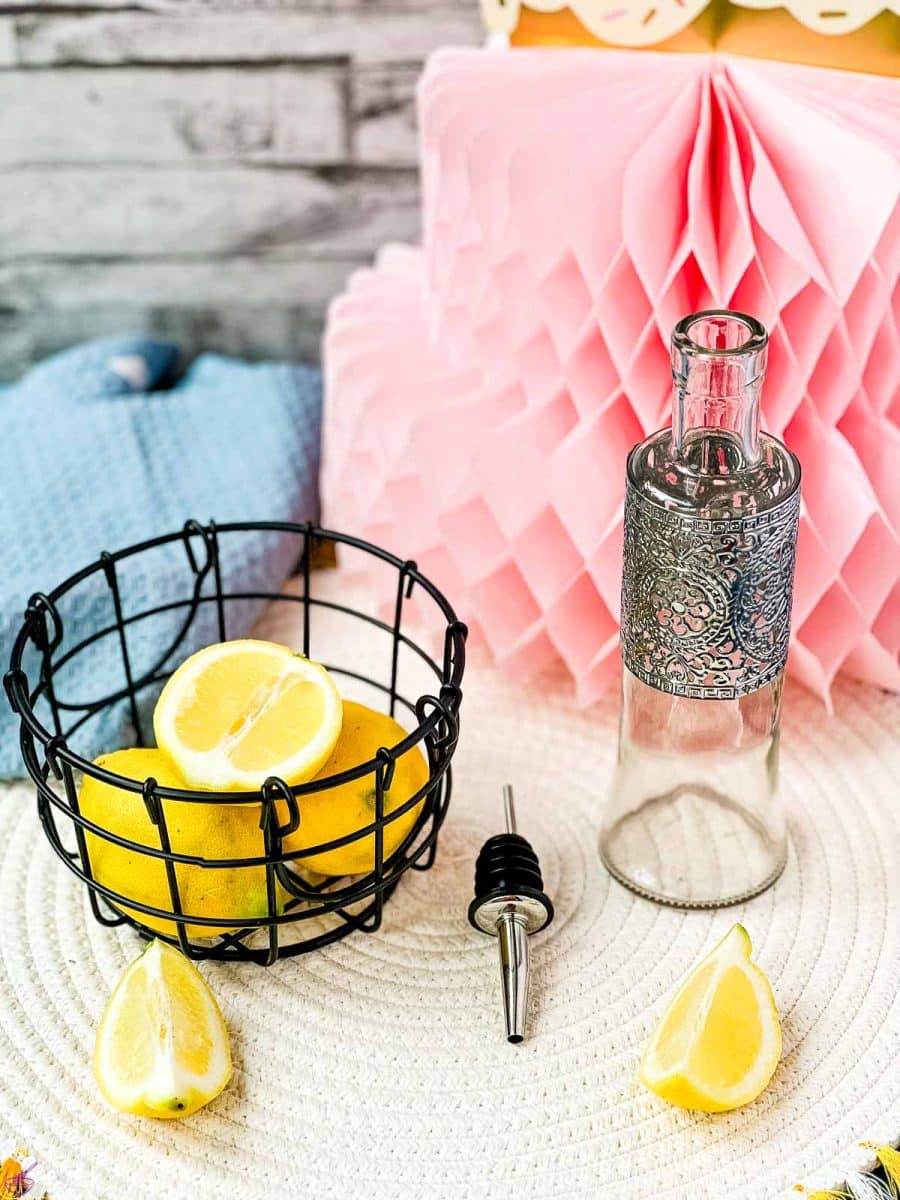 Lemons in wire basket next to bottle and pouring spout.