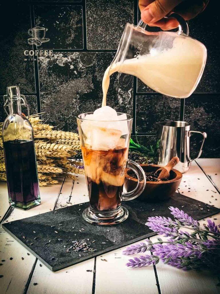 Gorgeous glass filled with iced lavender coffee, poured over with milk.