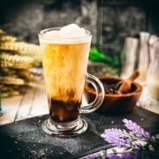 Gorgeous glass filled with iced lavender latte on dark slate plate.