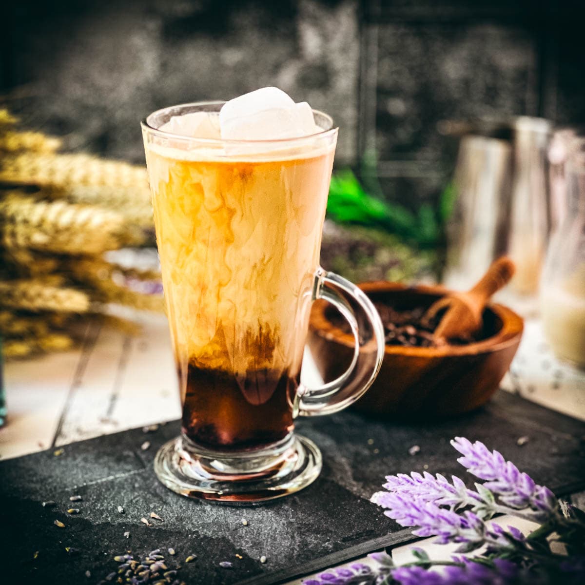 Gorgeous glass filled with iced lavender latte on dark slate plate.