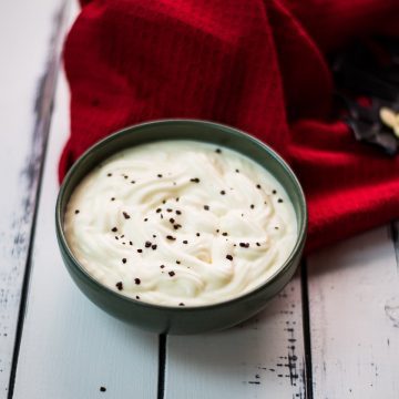 Gorgeous green bowl on white wooden board filled with delicious white chocolate pudding.