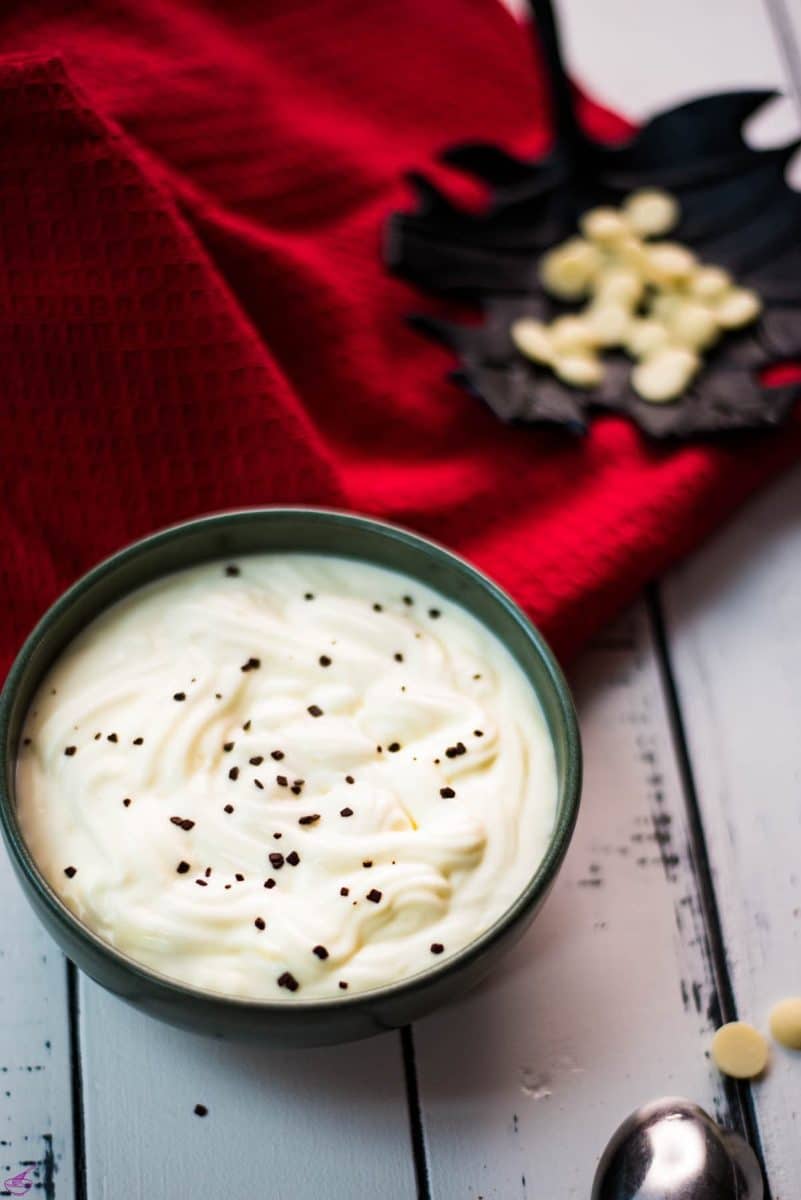 Gorgeous green bowl on white wooden board filled with delicious white chocolate pudding.