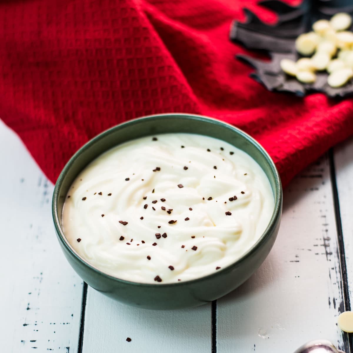 Gorgeous green bowl on white wooden board filled with delicious white chocolate pudding.