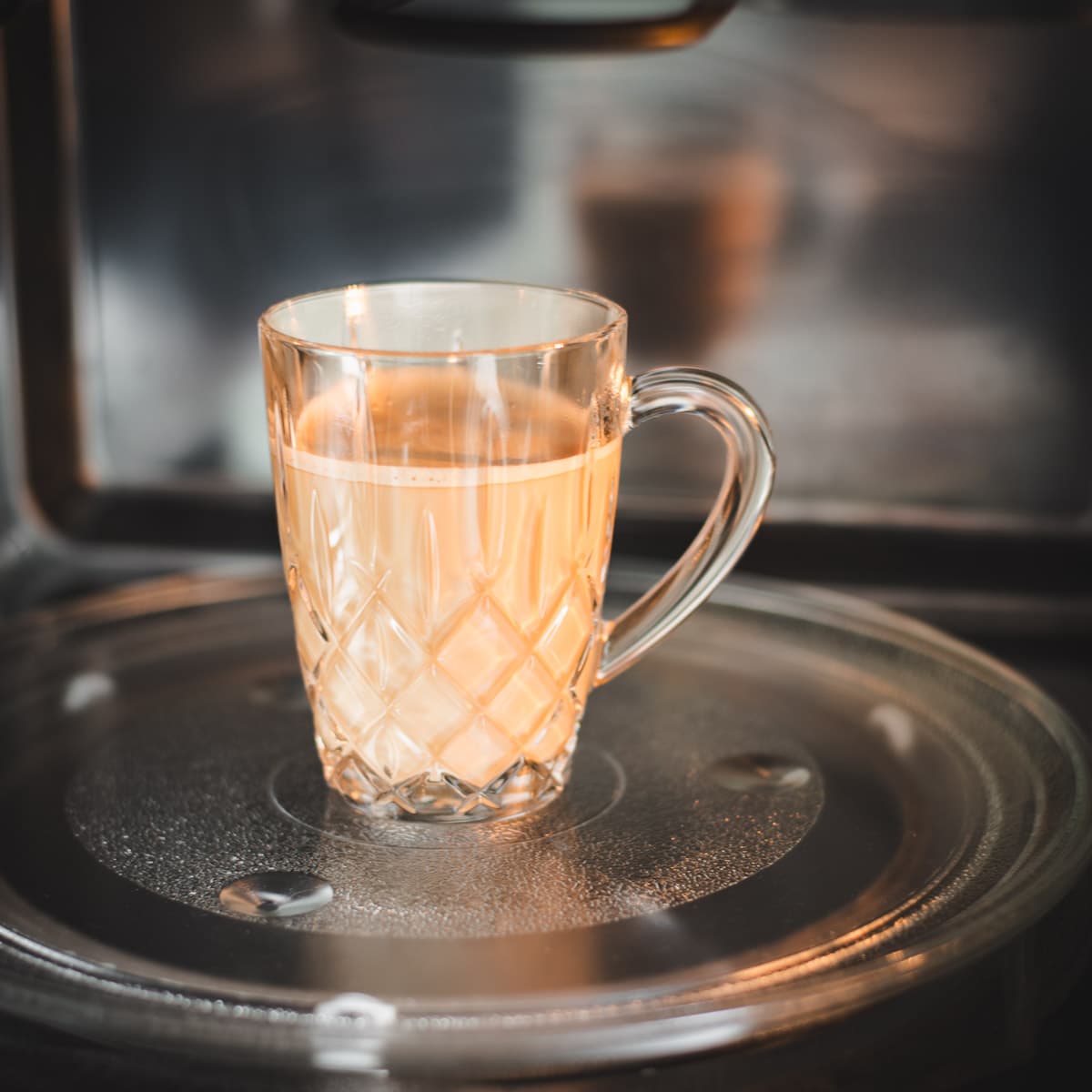 Mug filled with milk coffee placed in microwave.