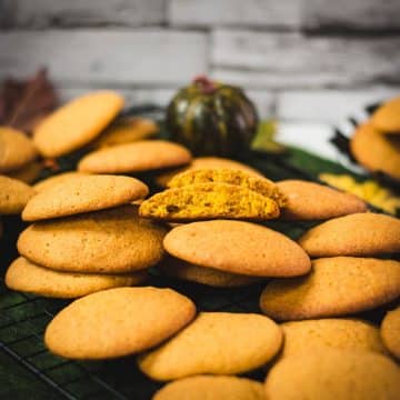 Pumpkin cookies stacked on top of each other on cooling grids with a nice view of the inside of the cookie.