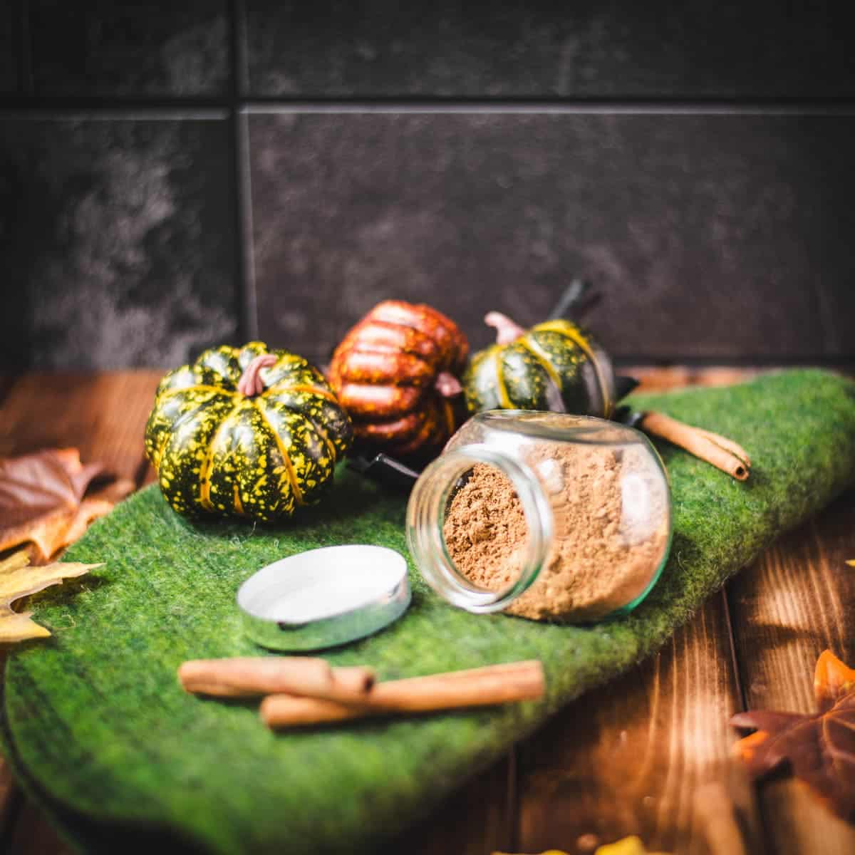 Spice jar filled with homemade pumpkin spice, placed on green felt mat.