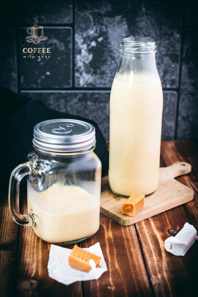 A bottle and a mason jar, filled with scrumptious homemade salted caramel coffee creamer. Placed on wooden board.