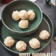 Charming coconut truffles in green bowl next to Christmas decoration.