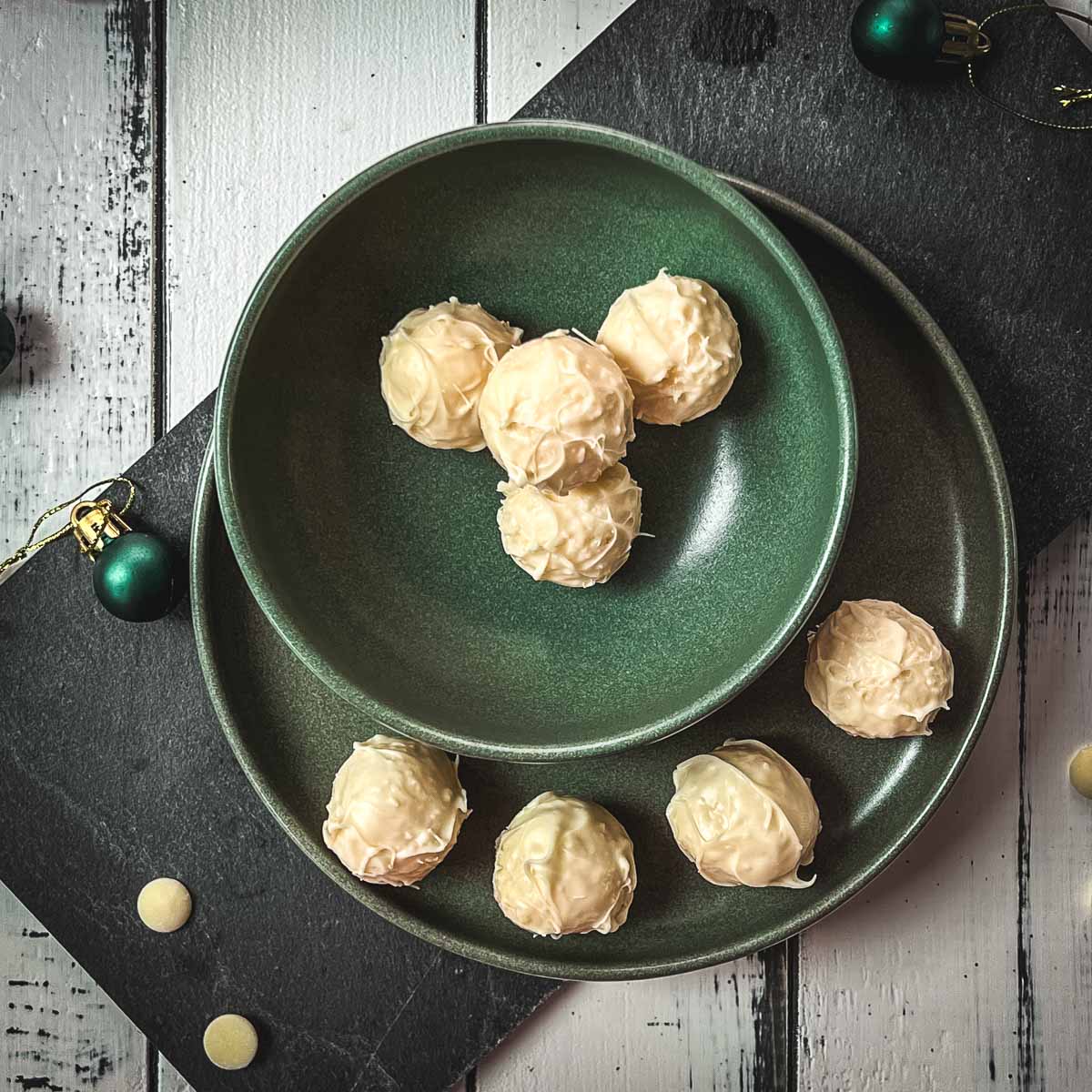 Charming coconut truffles in green bowl next to Christmas decoration.