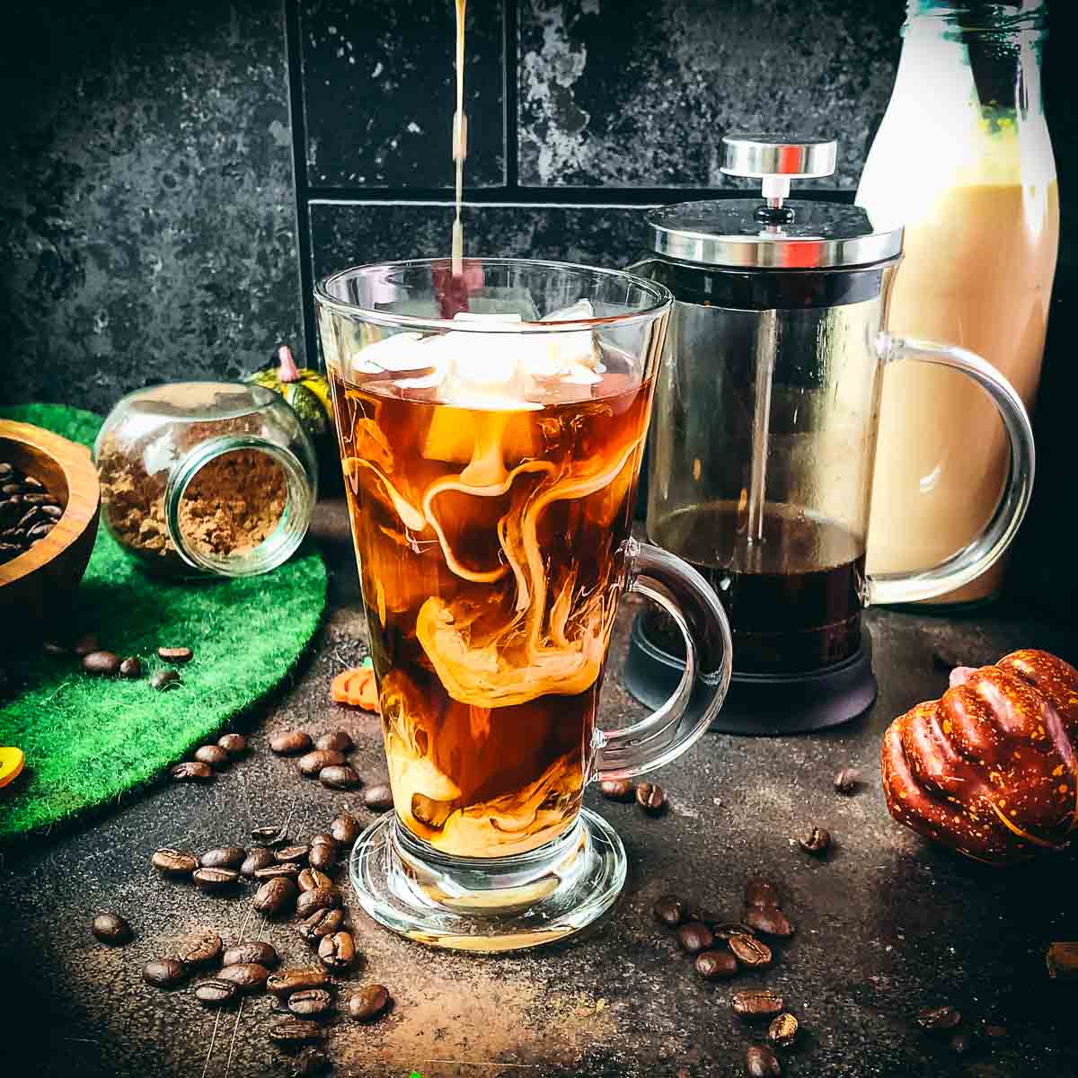 Gorgeous marbled pumpkin cream cold brew, placed next to a french press.