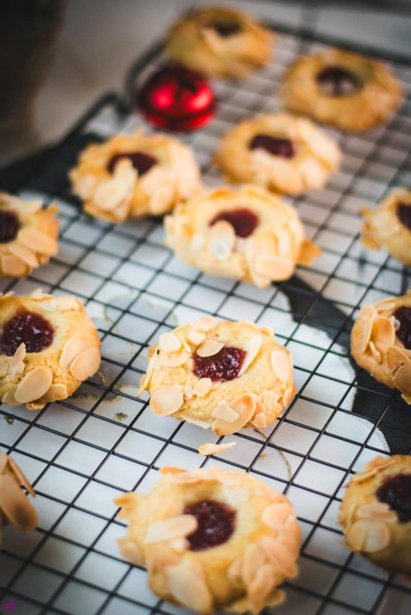 Delectable raspberry almond thumbprint cookies placed on a cooling rack.