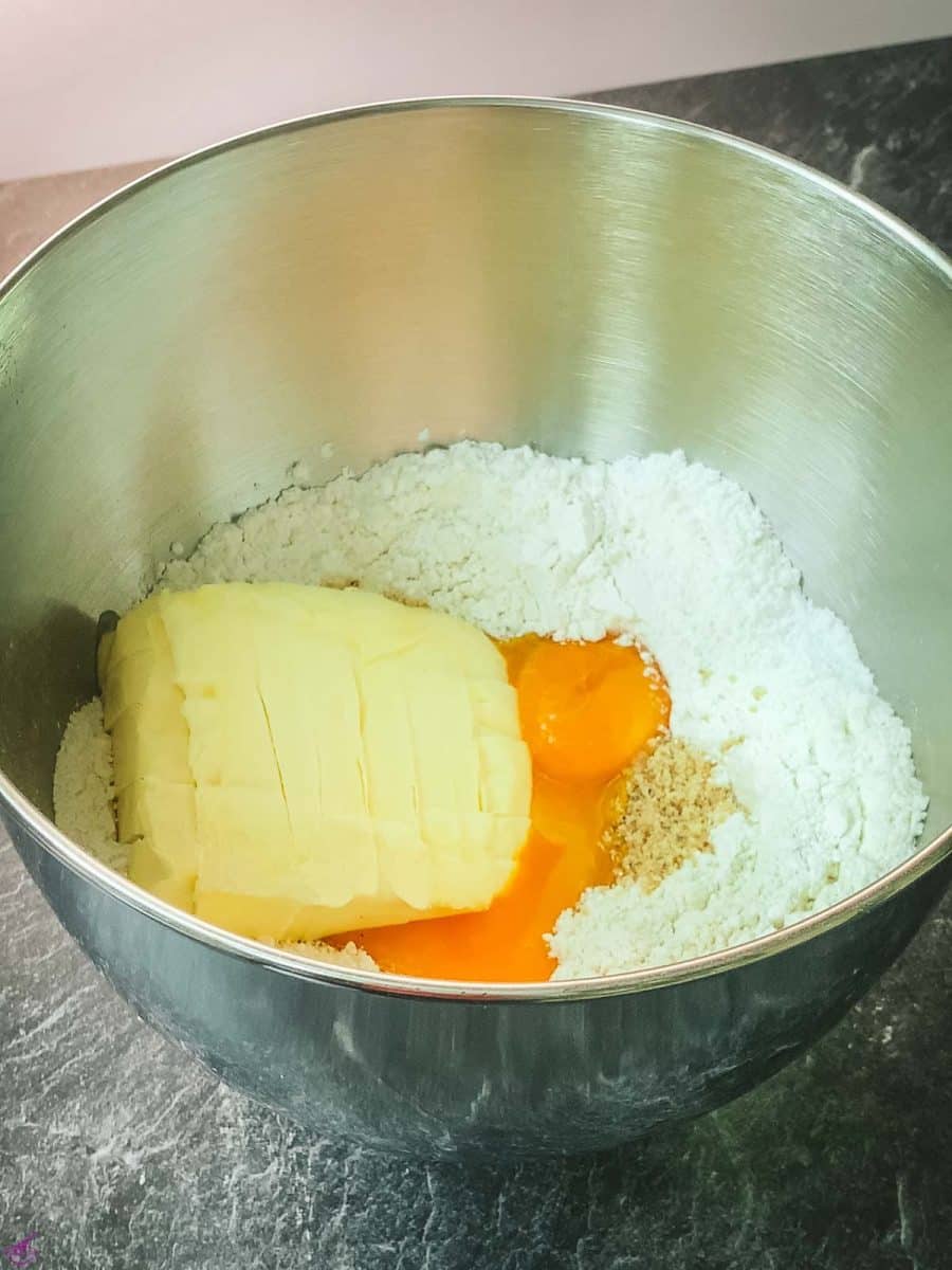 Make a dent in the center and add the remaining ingredients in order (powdered sugar, vanilla sugar, grated hazelnuts, yolks, butter in pieces).