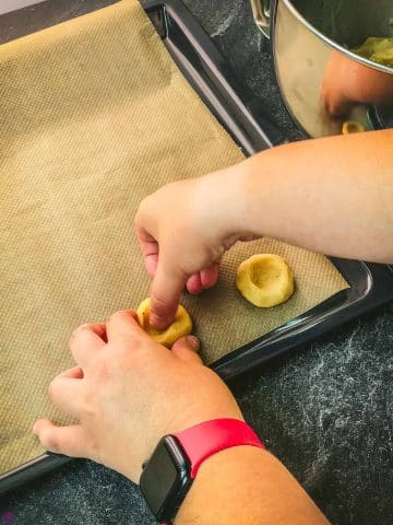 Use of your thumb to indent the center of each cookie ball.