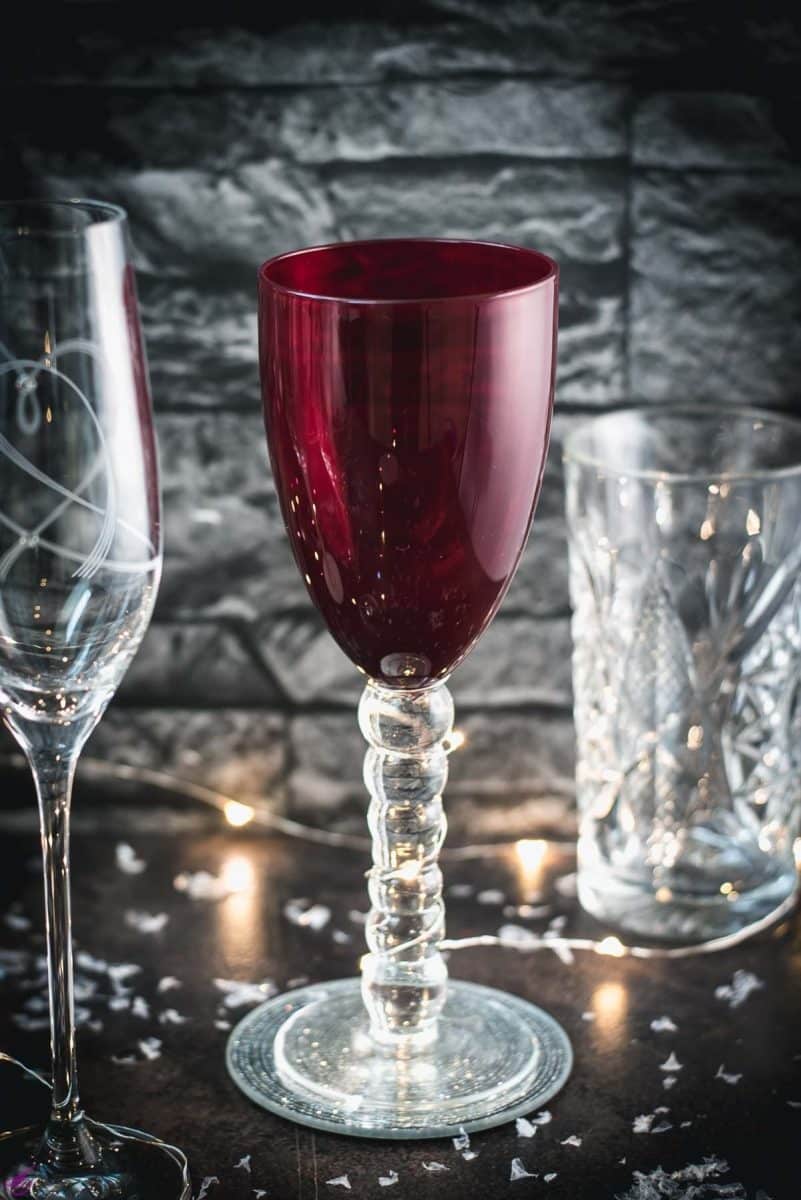 A variety of gorgeous wine, sparkling wine, and collins glasses placed in dark room.