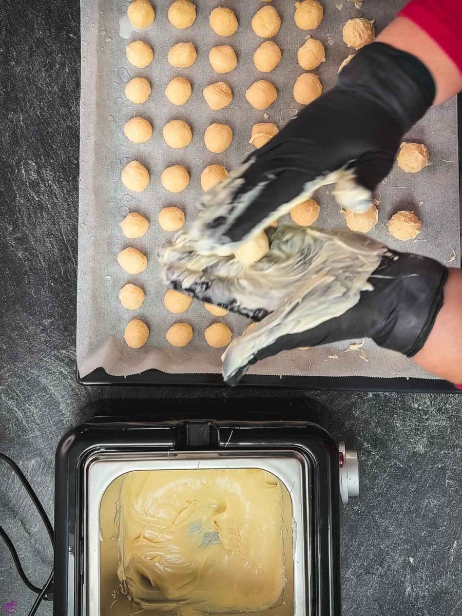 Roll the coconut balls between your white chocolate-covered hands.