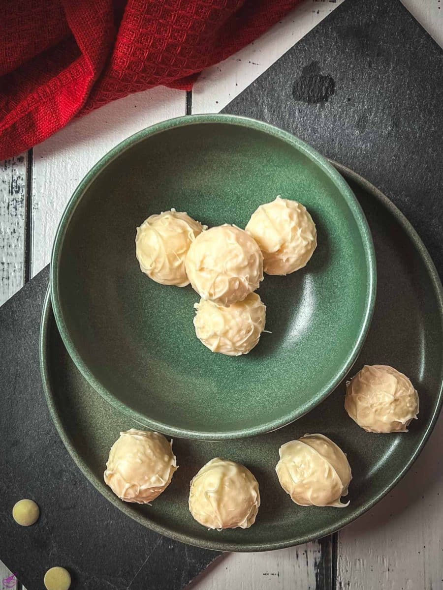 Charming coconut truffles in green bowl next to Christmas decoration.