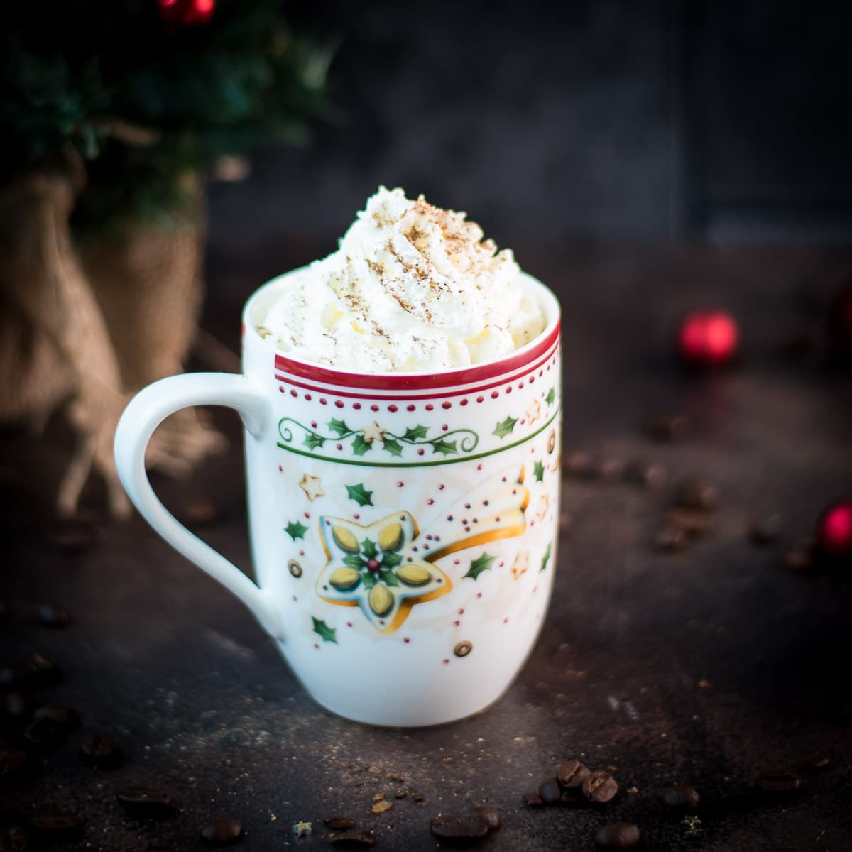 Scrumptious eggnog latte with whipped cream topping and dusted with cinnamon, served in gorgeous Christmassy mug.