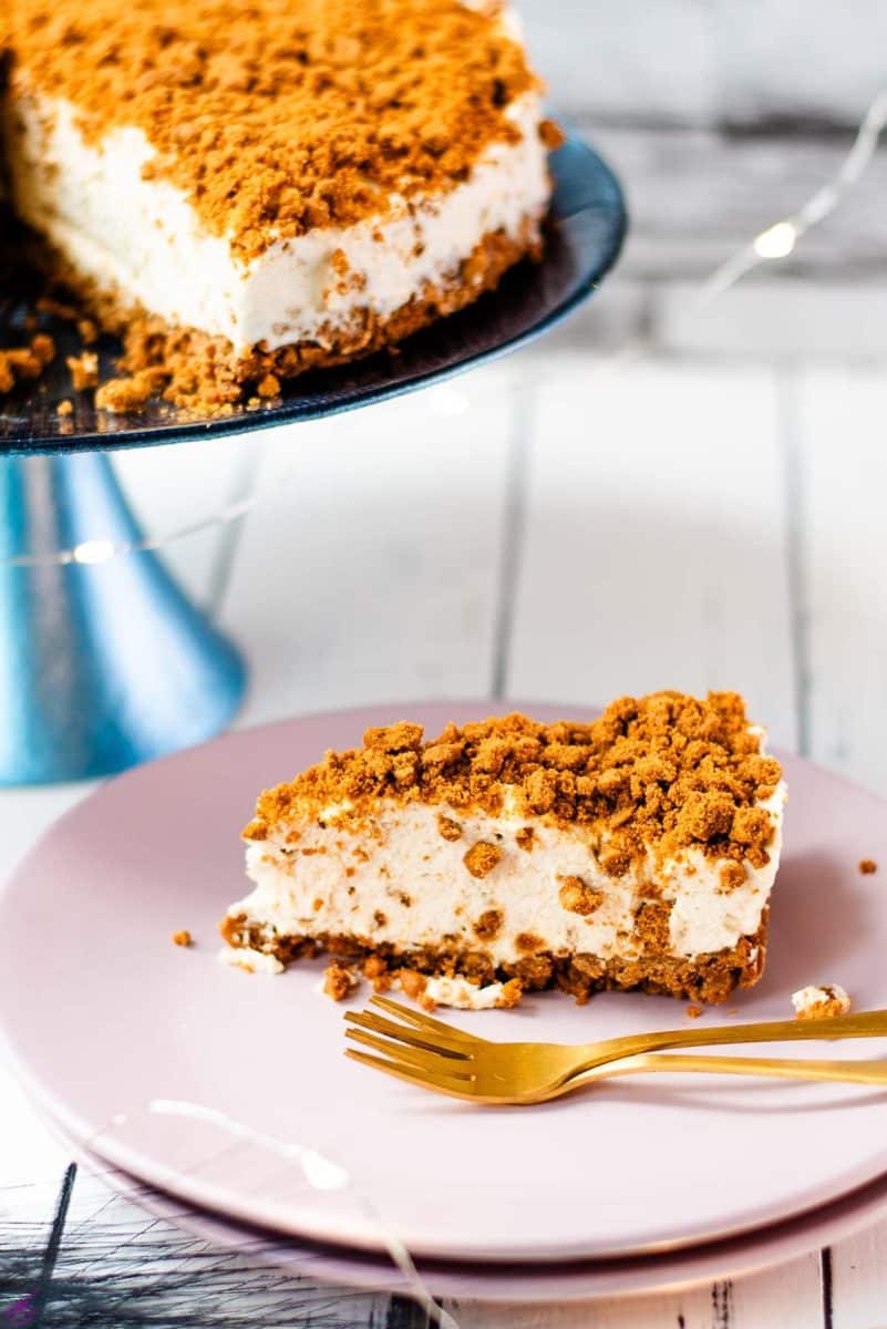 Gorgeous no bake Biscoff cheesecake slice on pink plate next to two golden forks.