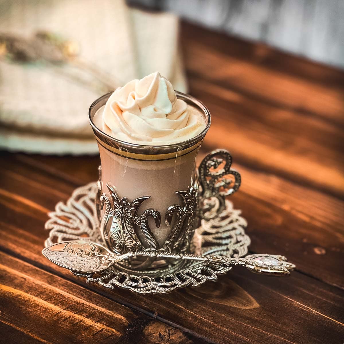 Medieval glass mug, filled with delicious strawberry white hot chocolate and topped with strawberry-flavored whipped cream.