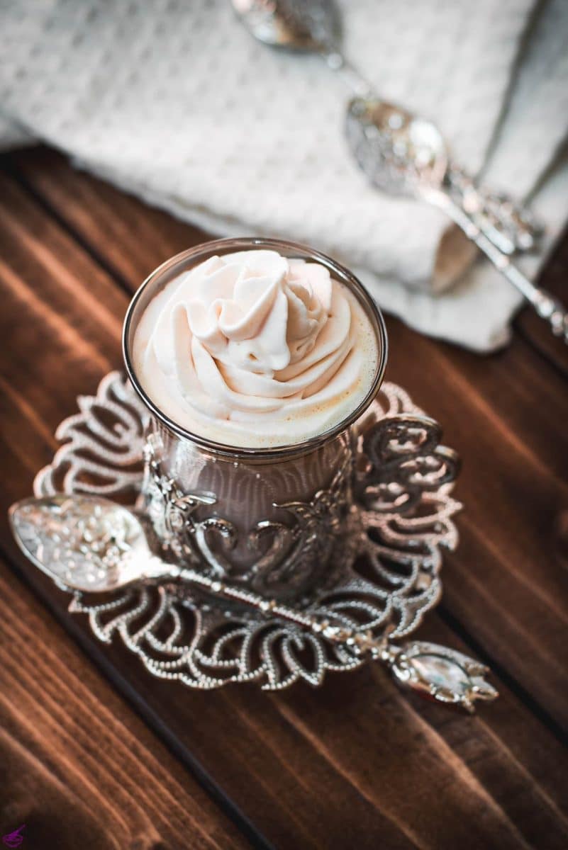 Medieval glass mug, filled with delicious strawberry white hot chocolate and topped with strawberry-flavored whipped cream.