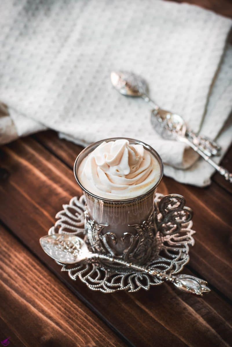 Medieval glass mug, filled with delicious strawberry white hot chocolate and topped with strawberry-flavored whipped cream.