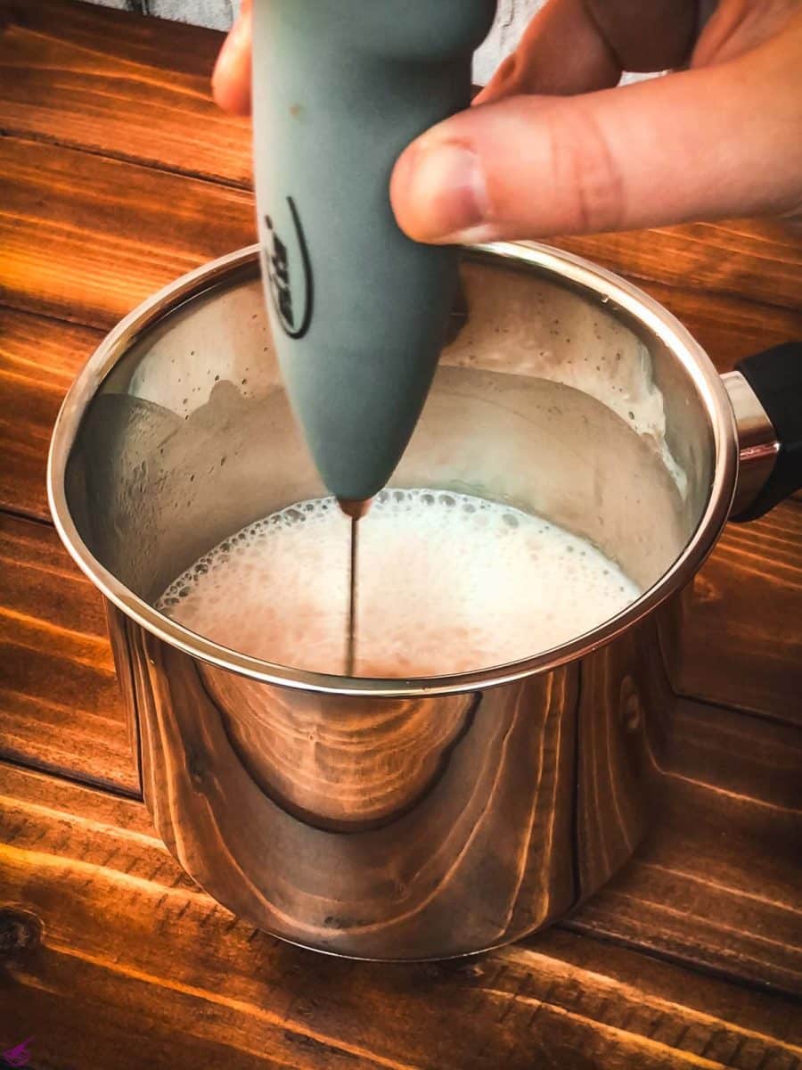 Froth the strawberry white hot chocolate mix with a handheld milk frother.