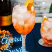 Wonderful layered Aperol Spritz! Tart and delicious! Placed on a mirror coaster on a blue wooden background.