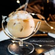 Gorgeous glass filled with iced cinnamon dolce latte, placed on black slate plate.