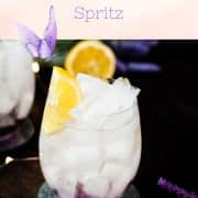 Gorgeous lavender spritz, garnished with lemon wedge and placed on shimmering coaster.