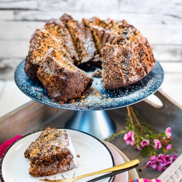 Gorgeous chocolate sprinkle spelt cake slices, placed on blue cake plate, and dusted with powdered sugar.