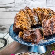 Gorgeous chocolate sprinkle spelt cake slices, placed on blue cake plate, and dusted with powdered sugar.