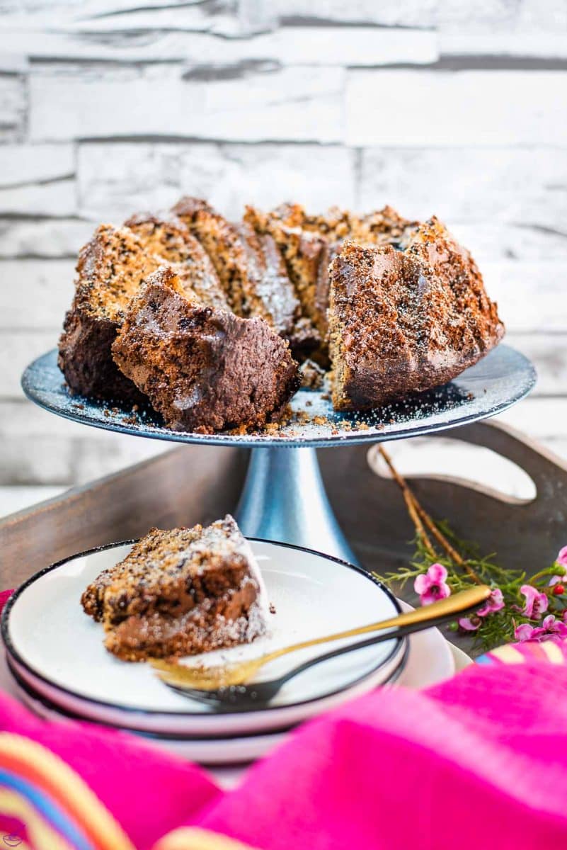 Gorgeous chocolate sprinkle spelt cake slices, placed on blue cake plate, and dusted with powdered sugar.