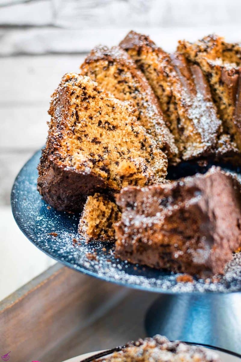 Gorgeous chocolate sprinkle spelt cake slices, placed on blue cake plate, and dusted with powdered sugar.