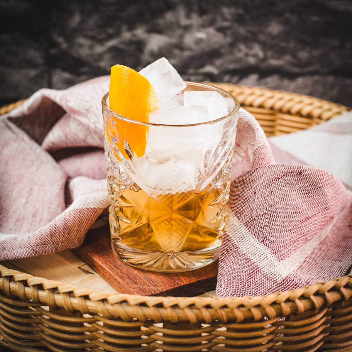 Gorgous glass filled with a delicious old fashioned drink. Placed on wooden coaster.