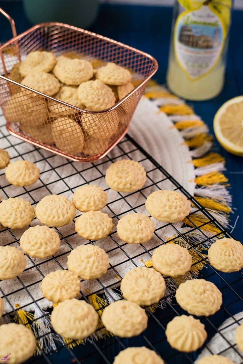 Gorgeous mini lemon sugar cookies placed on a cooling rack on a blue wooden ground.