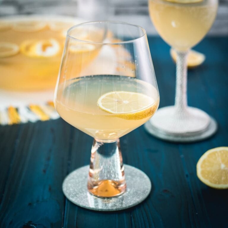Two glassed filled with lemon punch. Garnished with a lemon slice and placed on a mirror coaster.