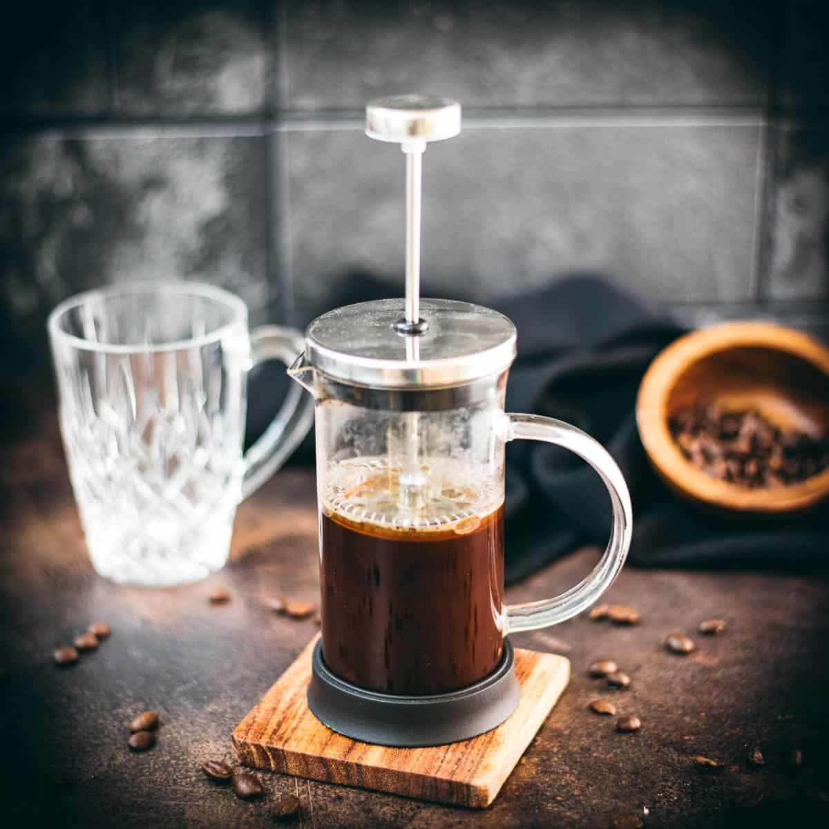 Delicious coffee in a french press, placed on dark brown ground.