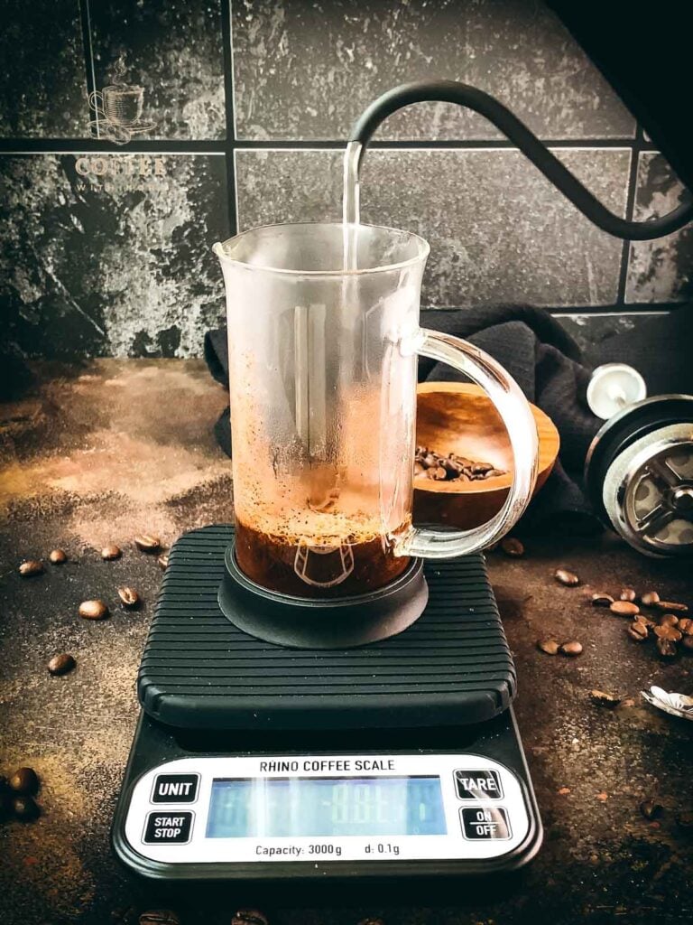 Pour hot water into the French press filled with coffee.