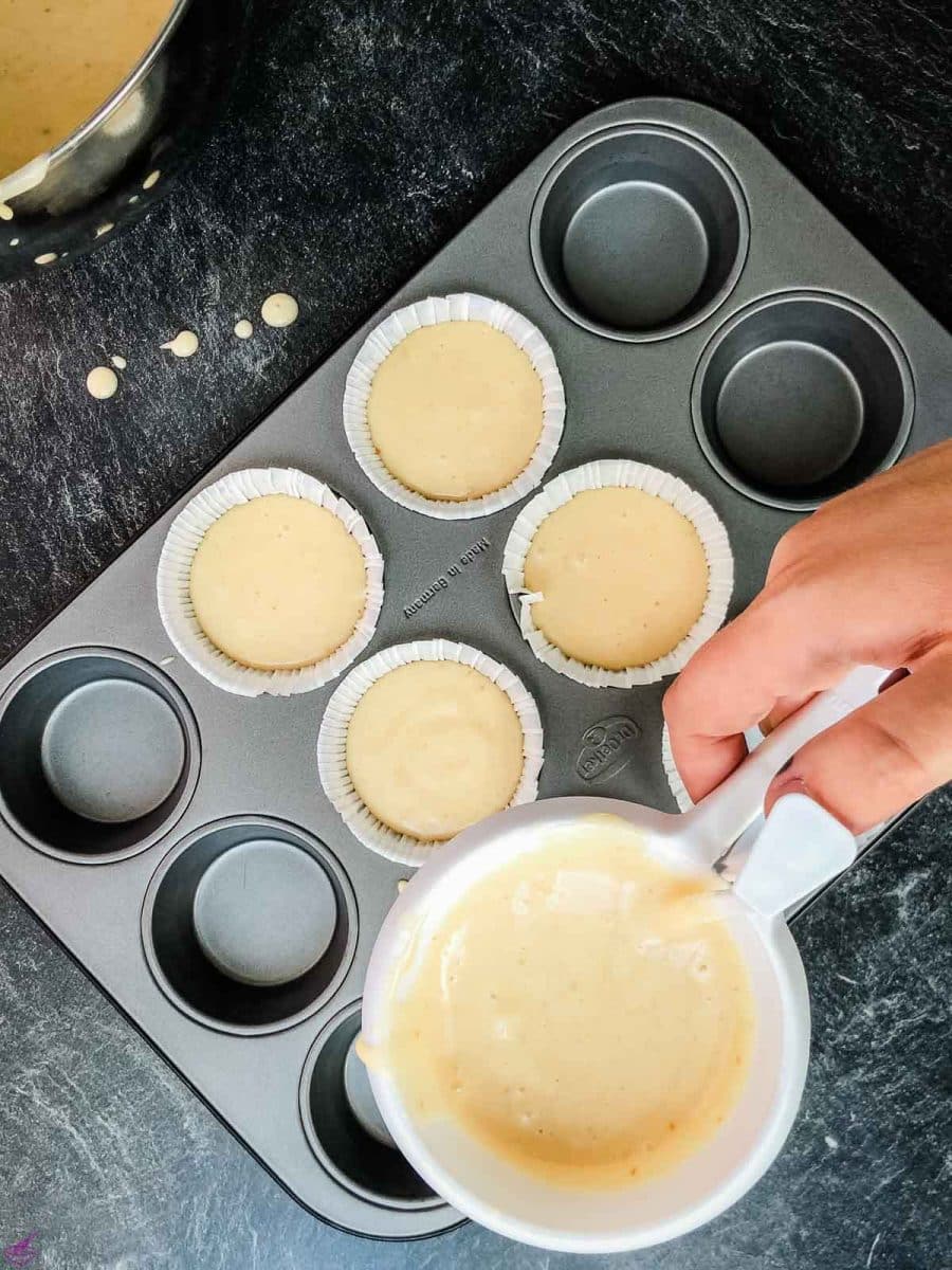 Pouring the muffin batter into the muffin liners using a handy batter dispenser tool.