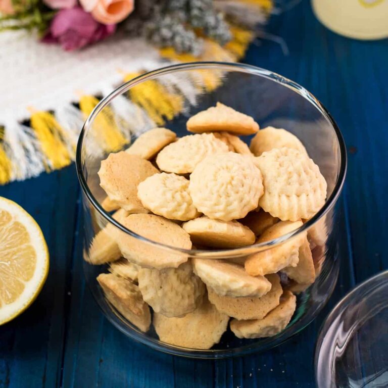 Gorgeous mini lemon sugar cookies placed in a glass jar on a blue wooden ground.
