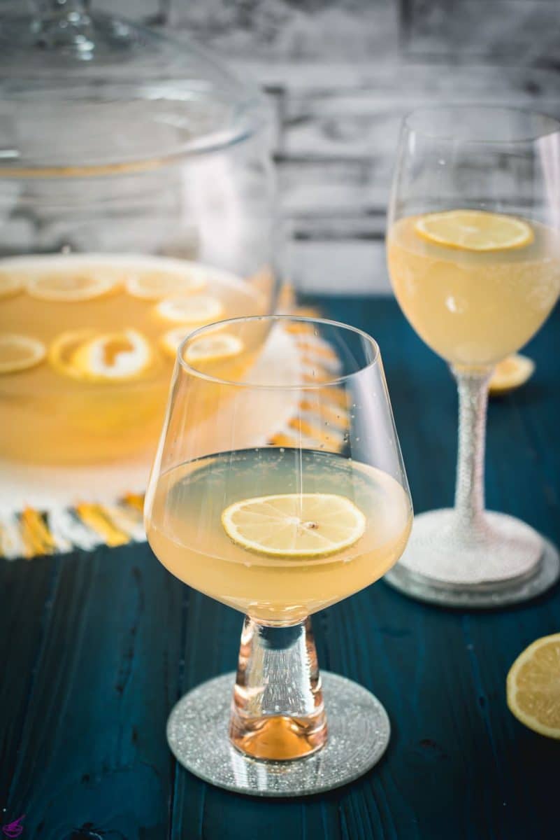 Two glassed filled with lemon punch. Garnished with a lemon slice and placed on a mirror coaster.