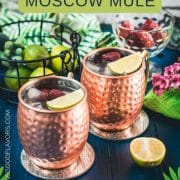 Gorgeous copper cups filled with delicious strawberry Moscow mule placed on blue wooden ground.