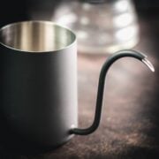 Black gooseneck kettle on dark ground.