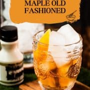 Gorgeous glass filled with maple old fashioned on wooden coaster. The drink is garnished with an orange zest and placed next to a stirring glass and a maple syrup bottle.